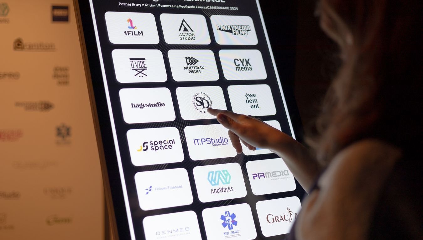 A person clicking on a logo displayed on an information kiosk screen. A person clicking on a logo displayed on an information kiosk screen.